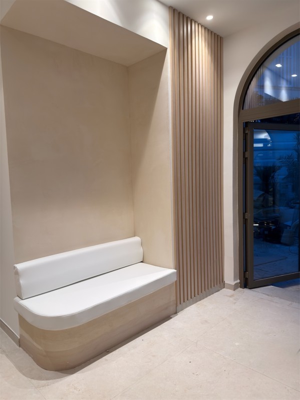 Agencement sur-mesure en bois avec claustra, habillage mural et banc d’accueil.